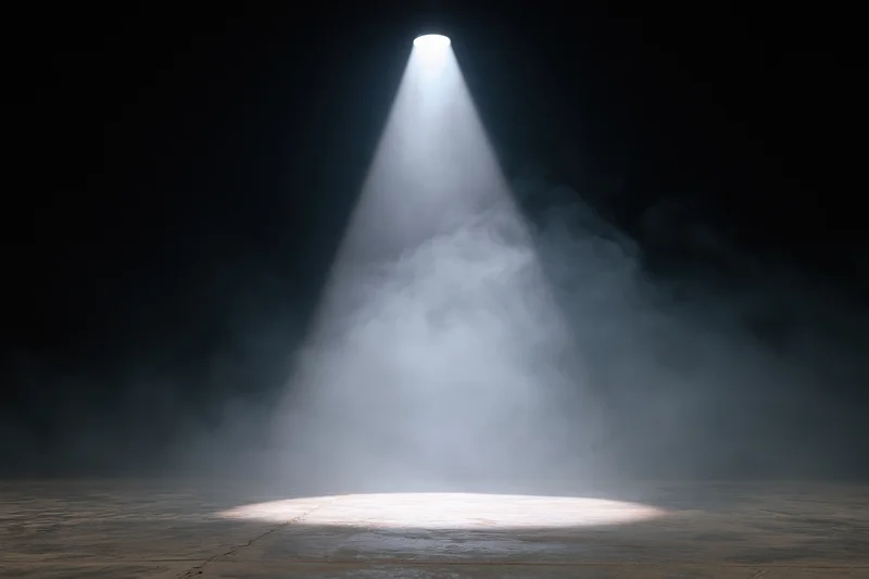 Single spotlight beam illuminating empty stage floor in dark theater