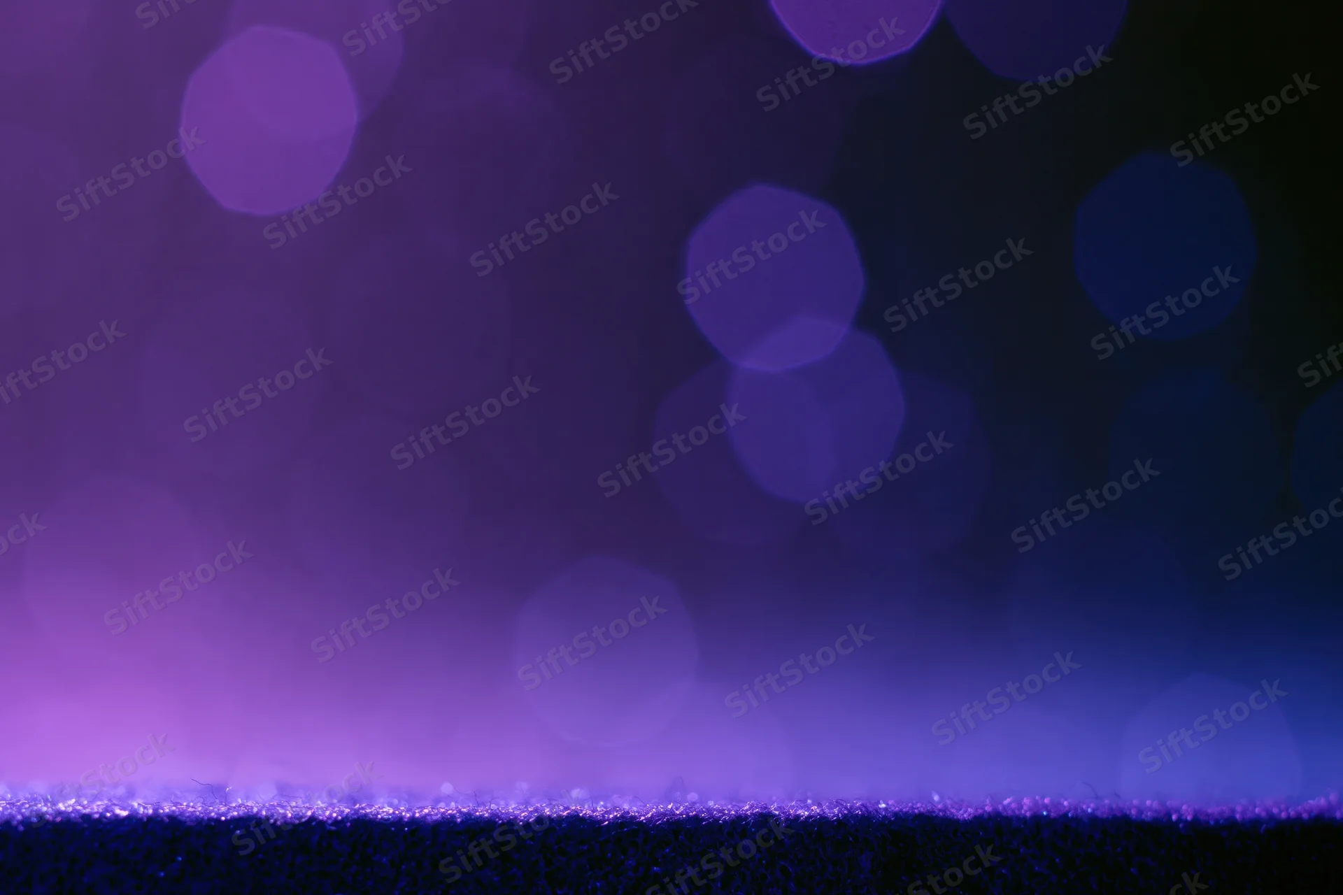 Dark studio backdrop with a glowing purple ledge and blurred bokeh lights above