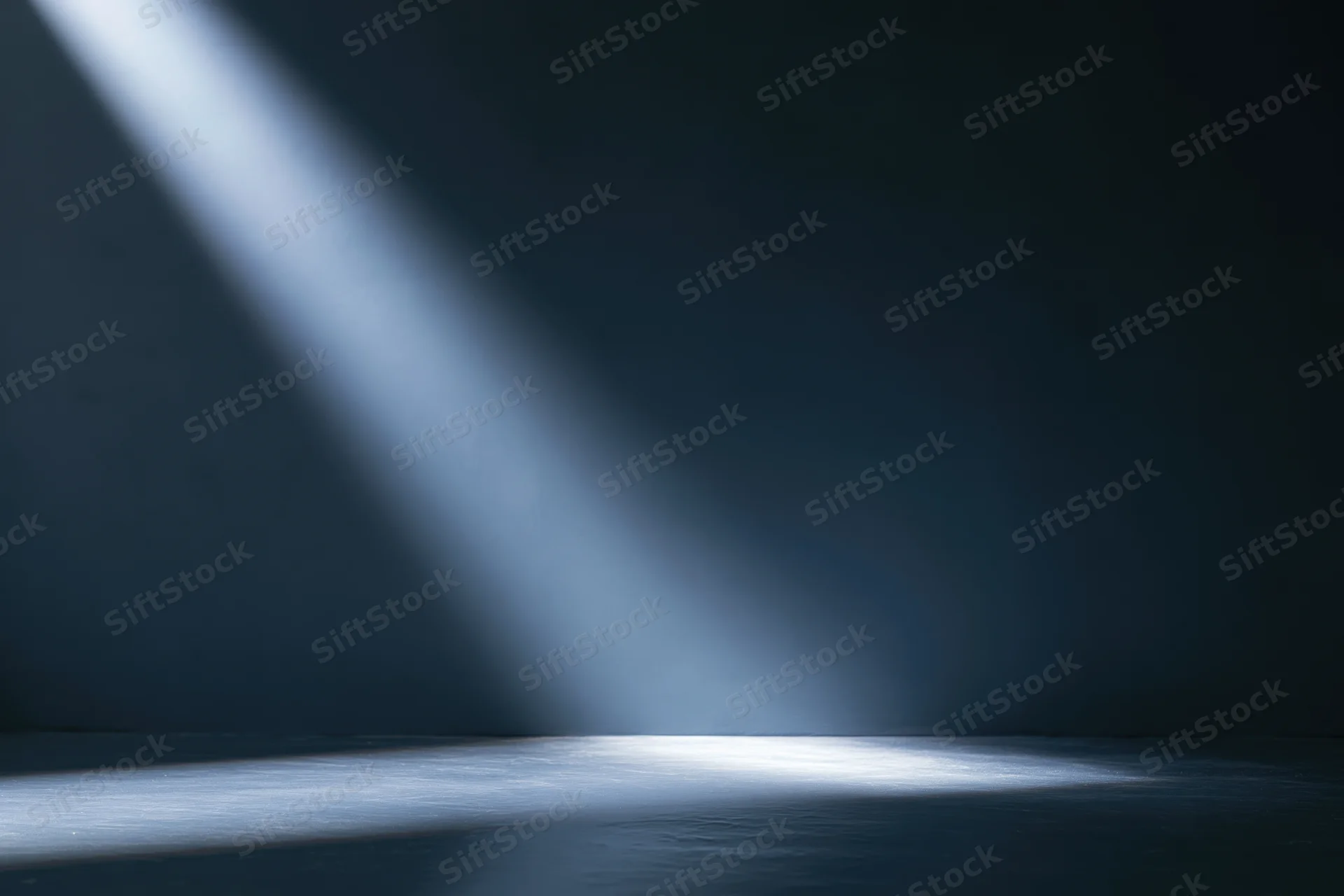 Single spotlight beam angled across dark studio floor