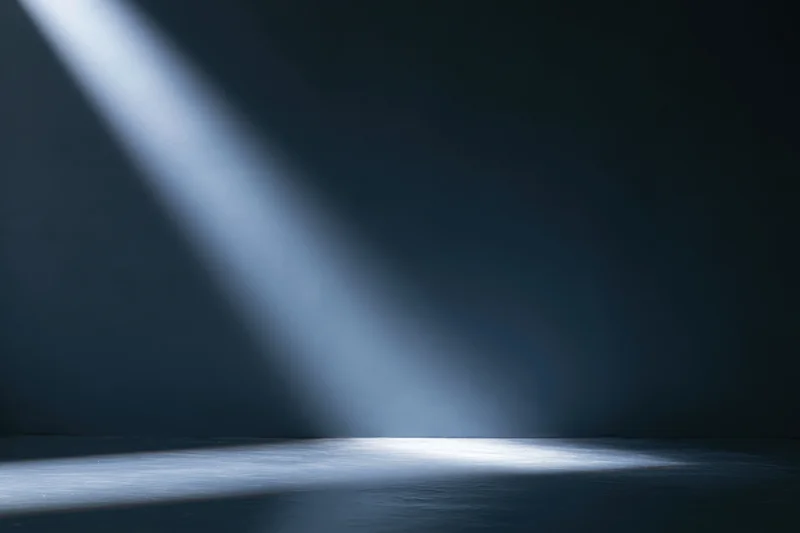 Single spotlight beam angled across dark studio floor