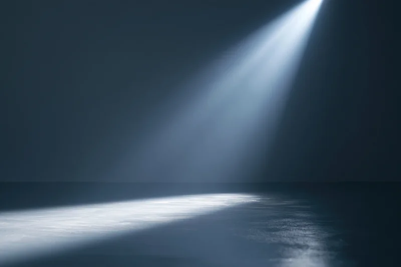 Single spotlight beam angled across dark studio floor
