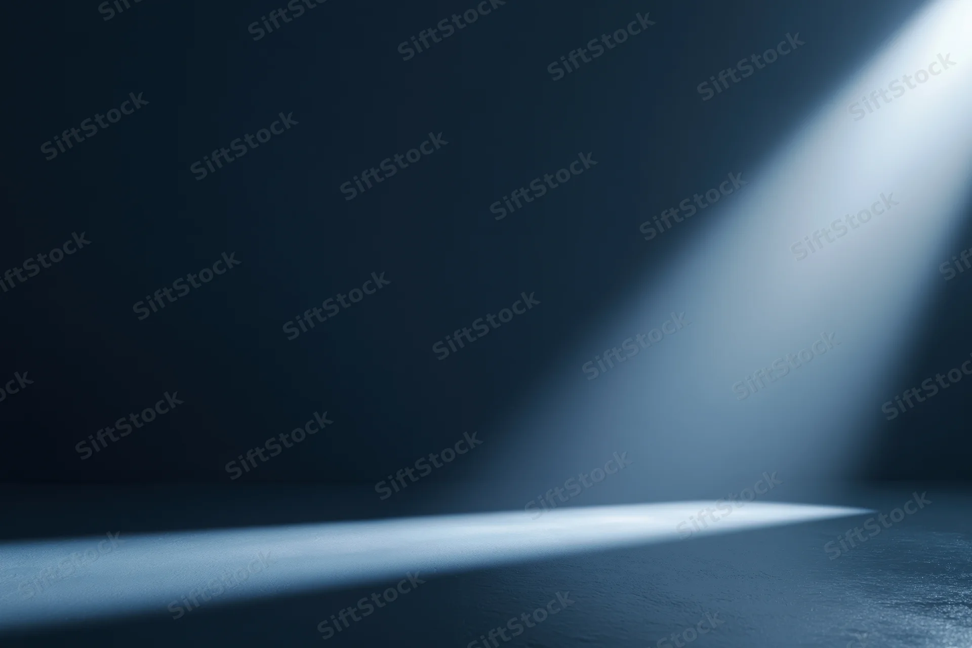 Angled spotlight beam on dark studio floor creating shadow and copyspace