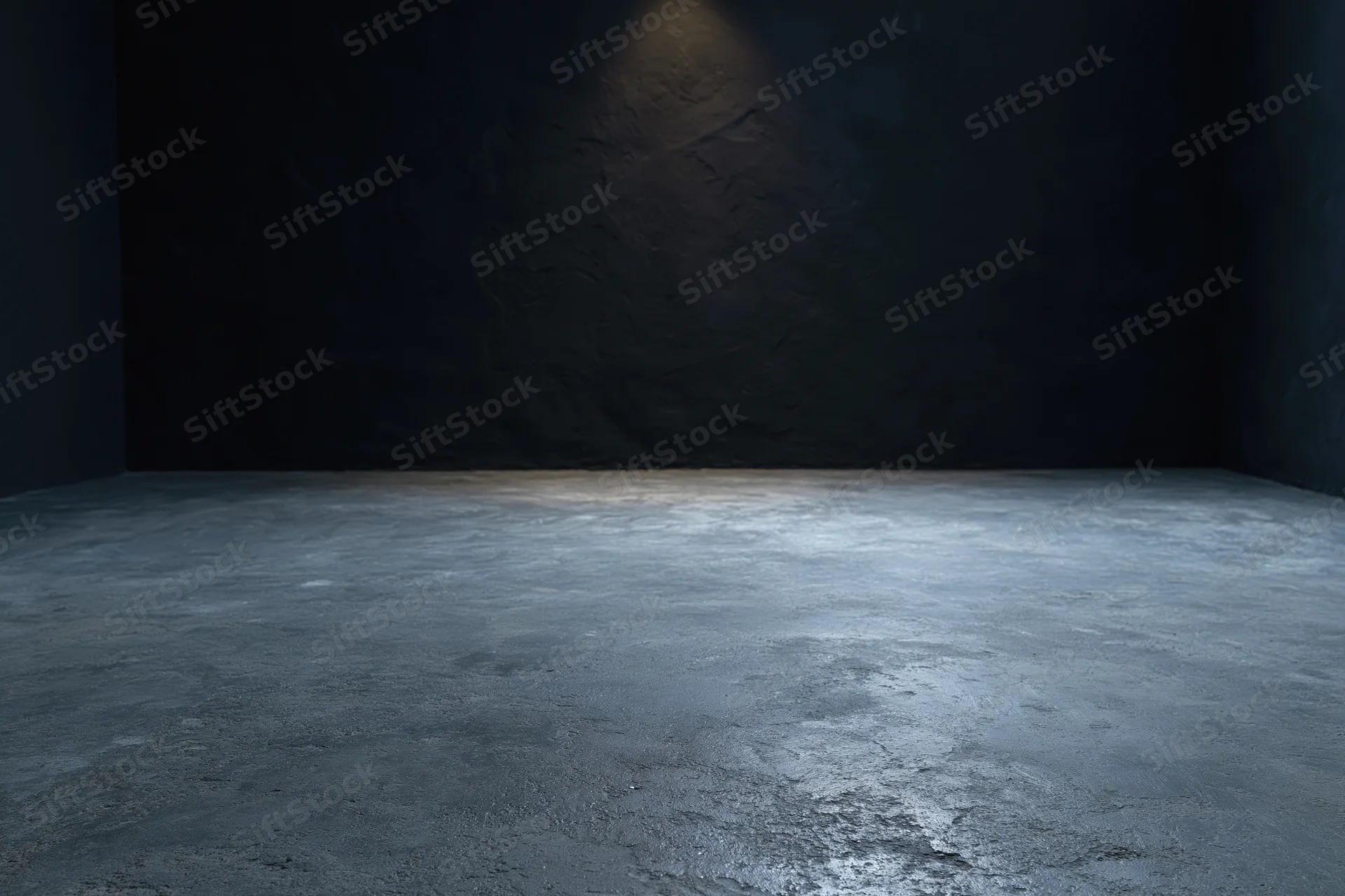 Dark empty studio interior with rough concrete floor and spotlighted wall