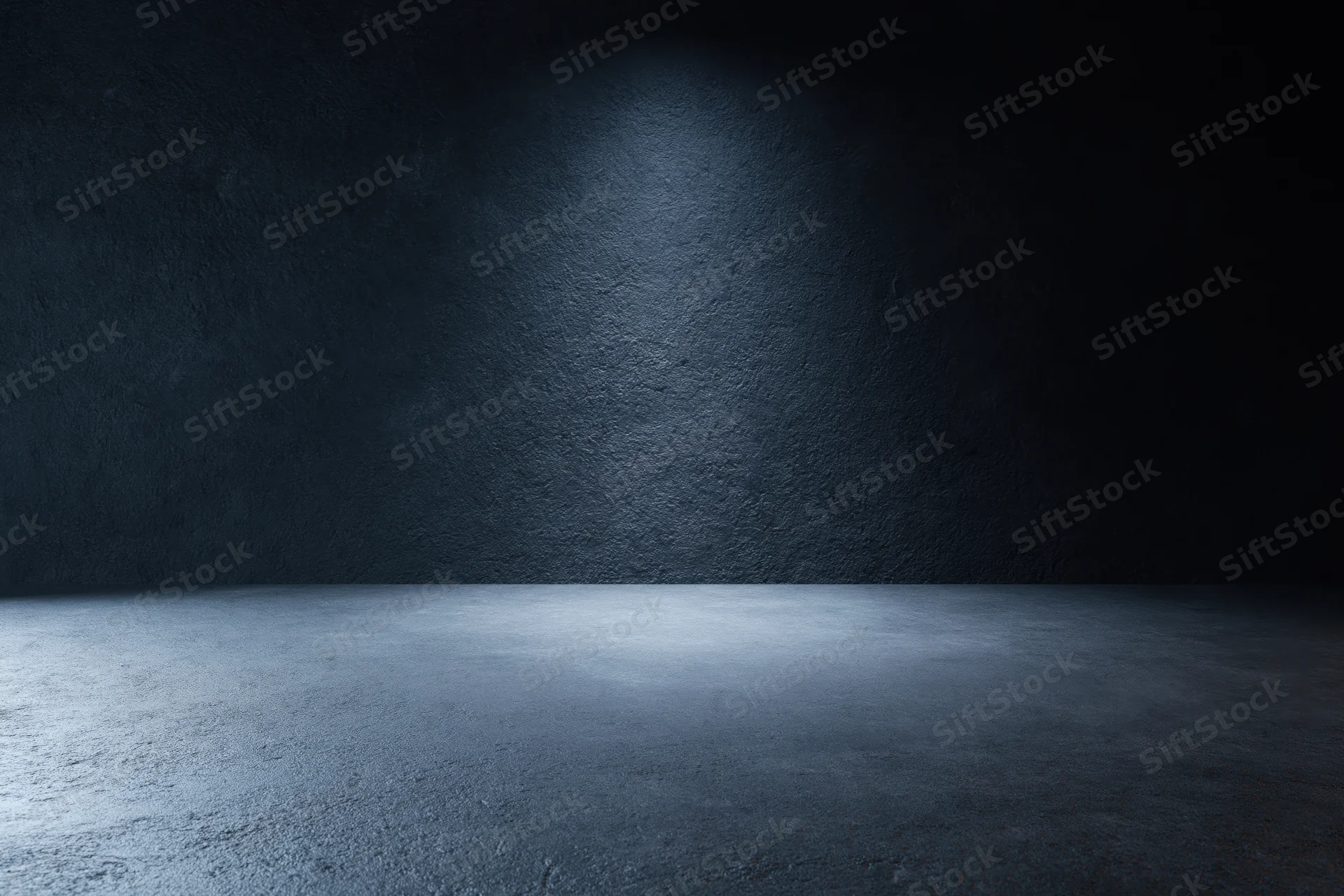 Empty dark studio room with textured concrete wall and floor under spotlight lighting