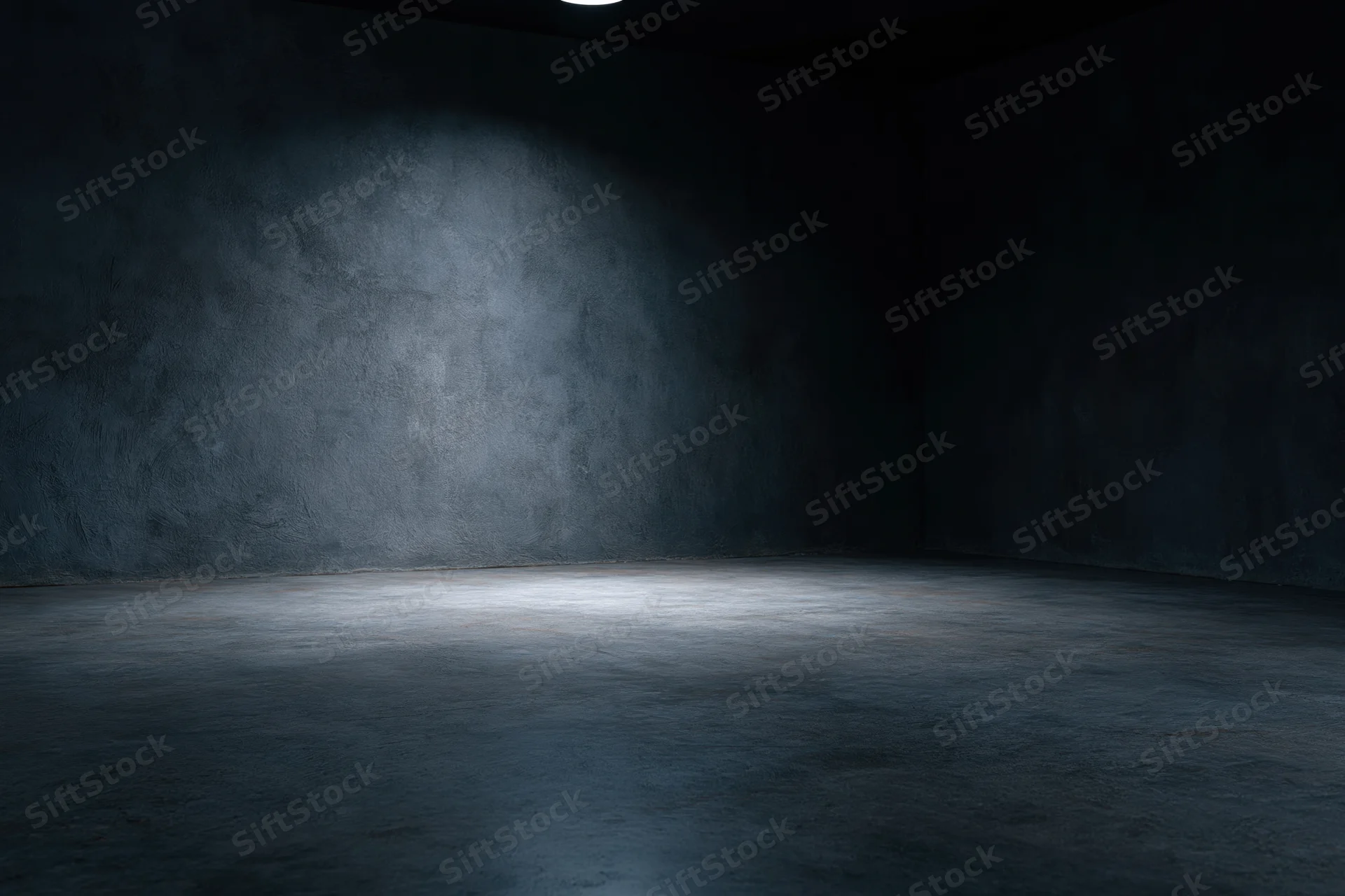 Empty dark studio room with concrete textured walls and floor lit by a single spotlight creating a moody atmosphere with copyspace
