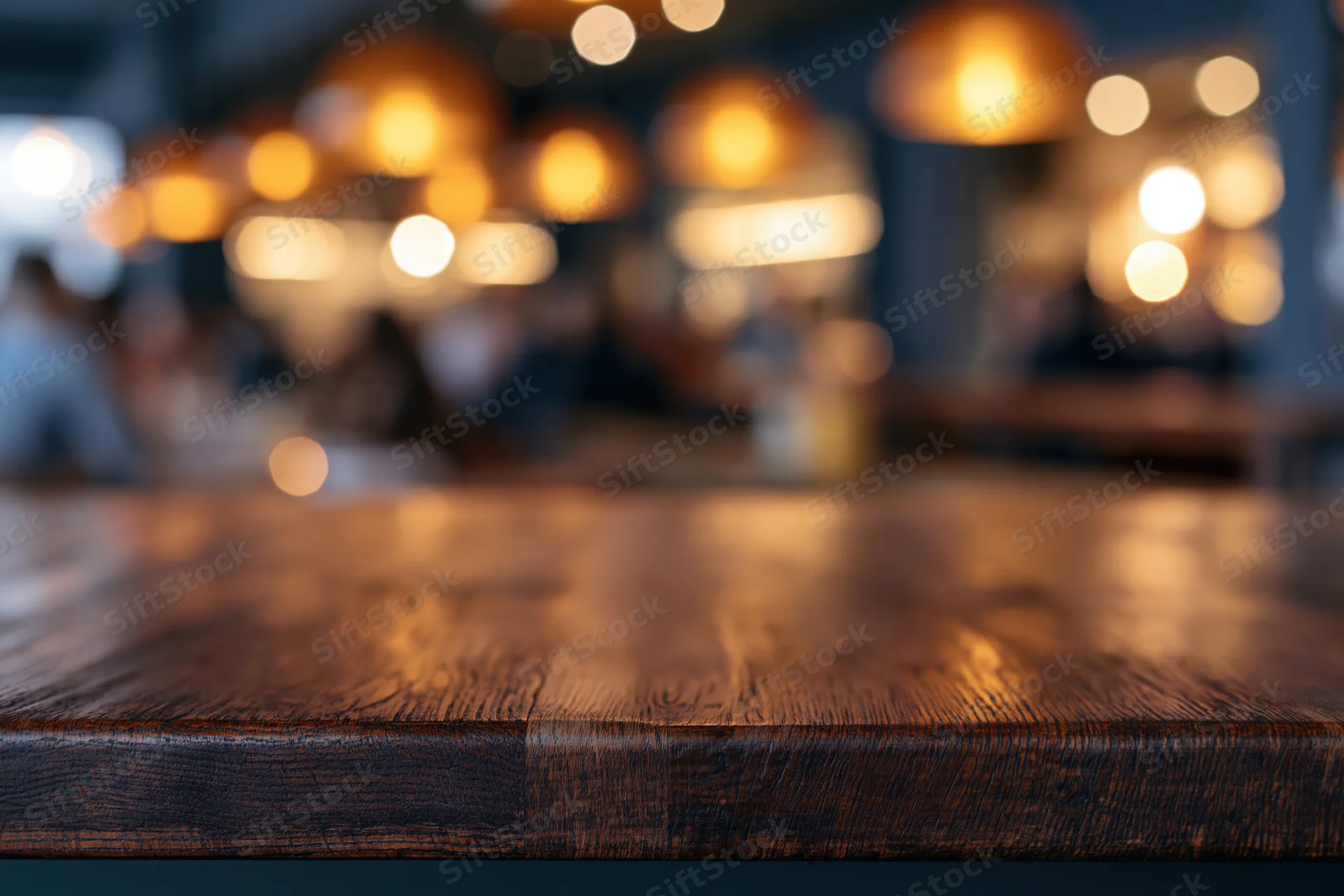 Dark wooden bar counter in sharp focus with blurred restaurant interior and warm lighting in background