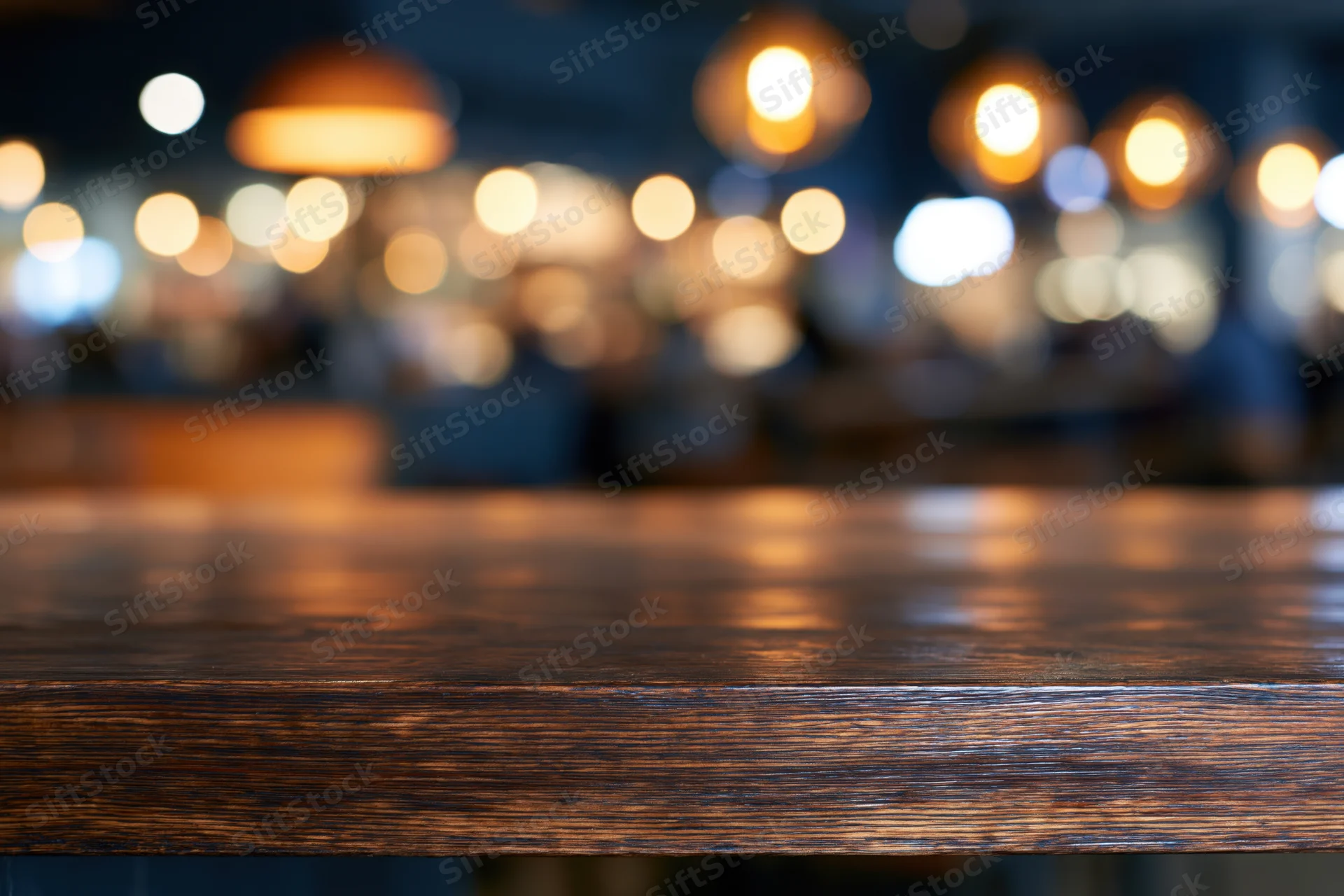 Dark wooden bar counter in sharp focus with blurred lights in background
