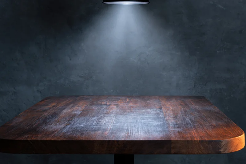 Dark wooden tabletop under spotlight in industrial studio setting