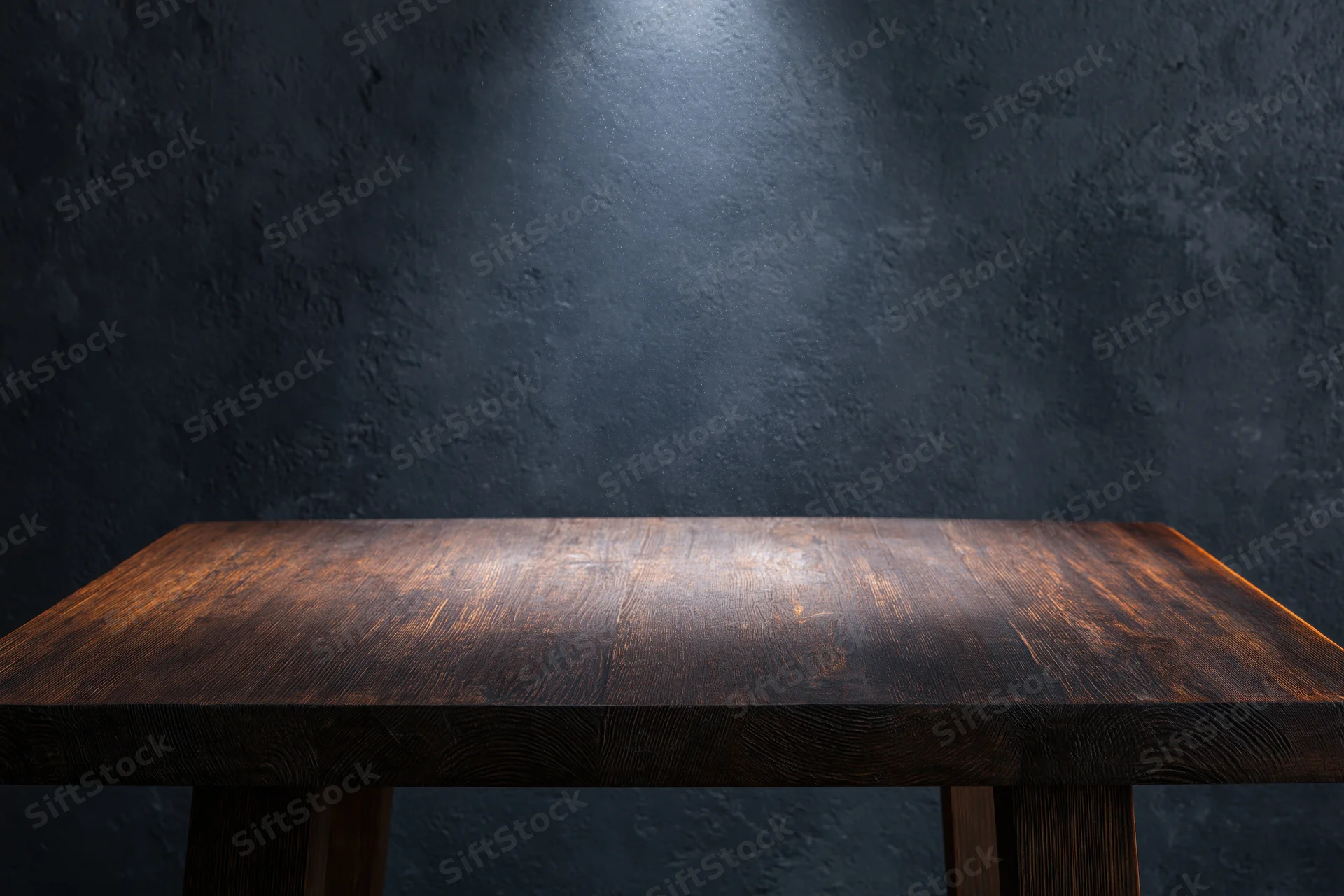 Empty dark wooden tabletop surface in front of textured dark wall with spotlight and copyspace