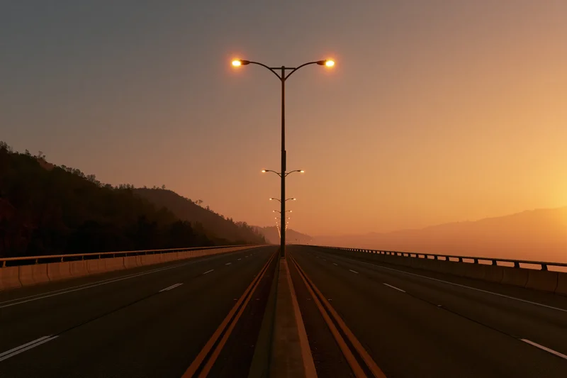 Empty four-lane highway stretching toward the horizon lined with streetlights at sunset