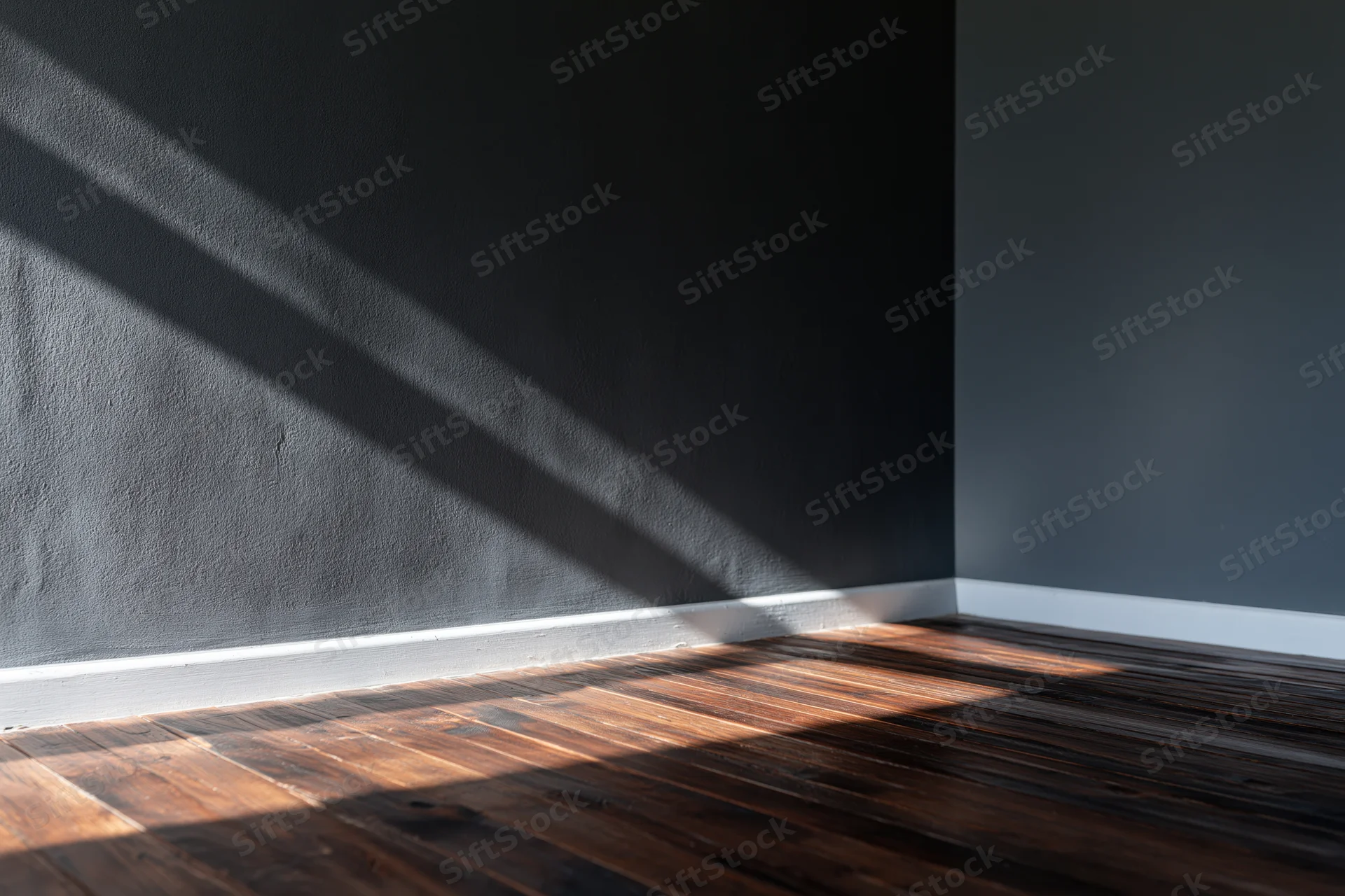 Empty interior room with dark charcoal matte wall and wooden floor, sunlight casting diagonal shadows across corner
