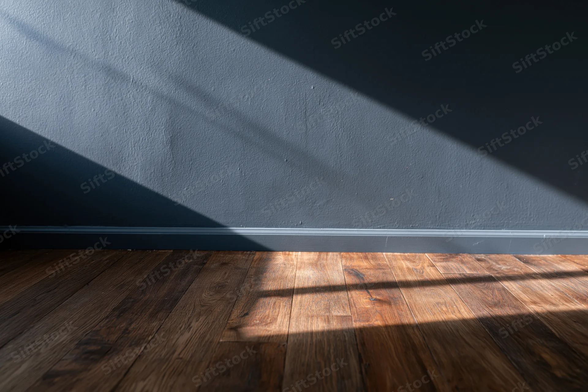 Empty interior room with dark charcoal matte wall and hardwood floor showing sunlight and shadows