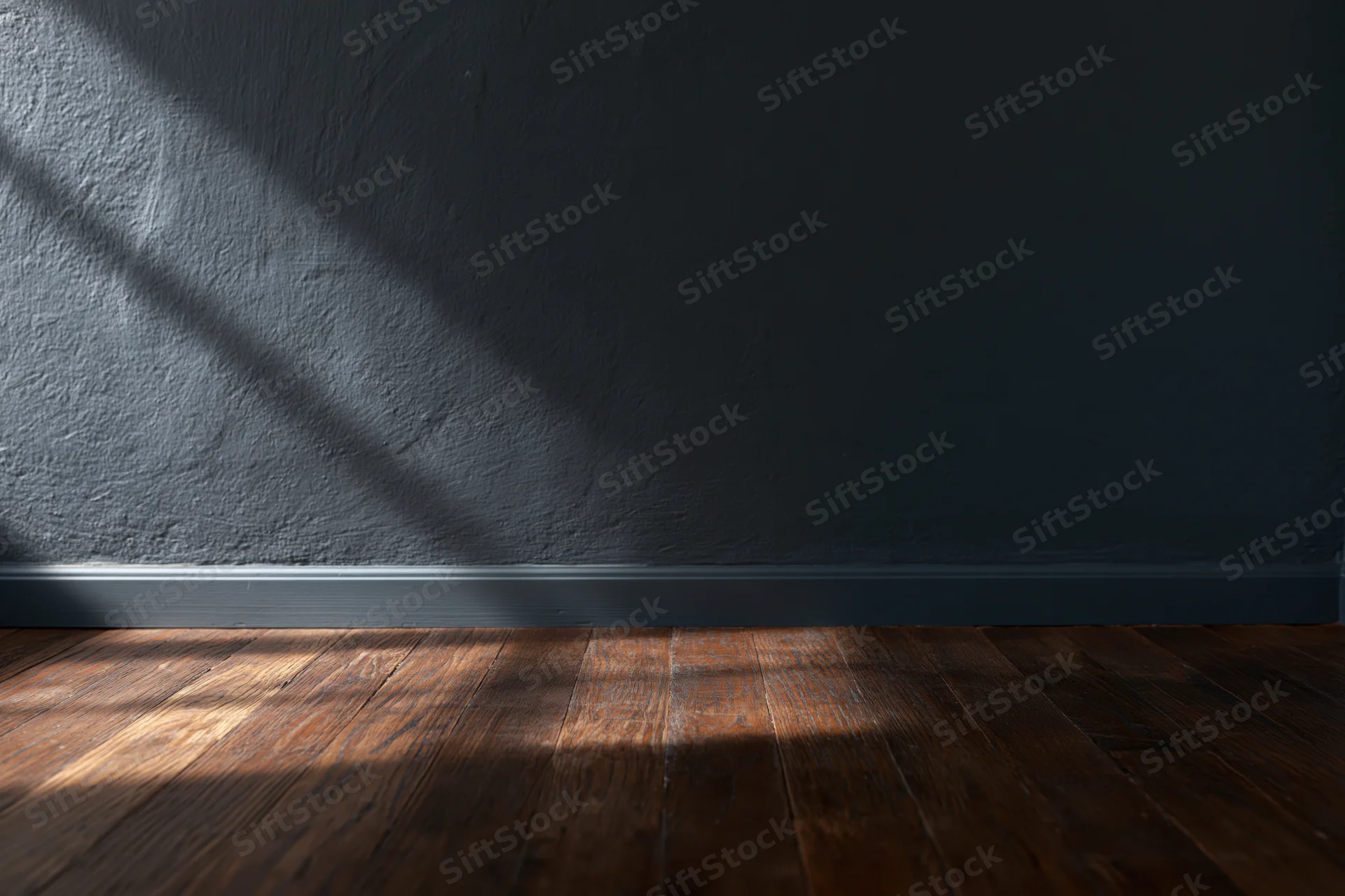 Empty interior room with dark charcoal matte wall and worn hardwood floor, sunlight casting diagonal shadow across surface
