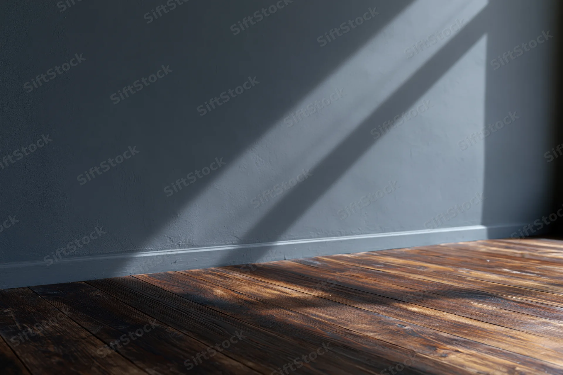 Empty interior room with dark charcoal matte wall and worn hardwood floor, sunlight casting diagonal shadow across corner
