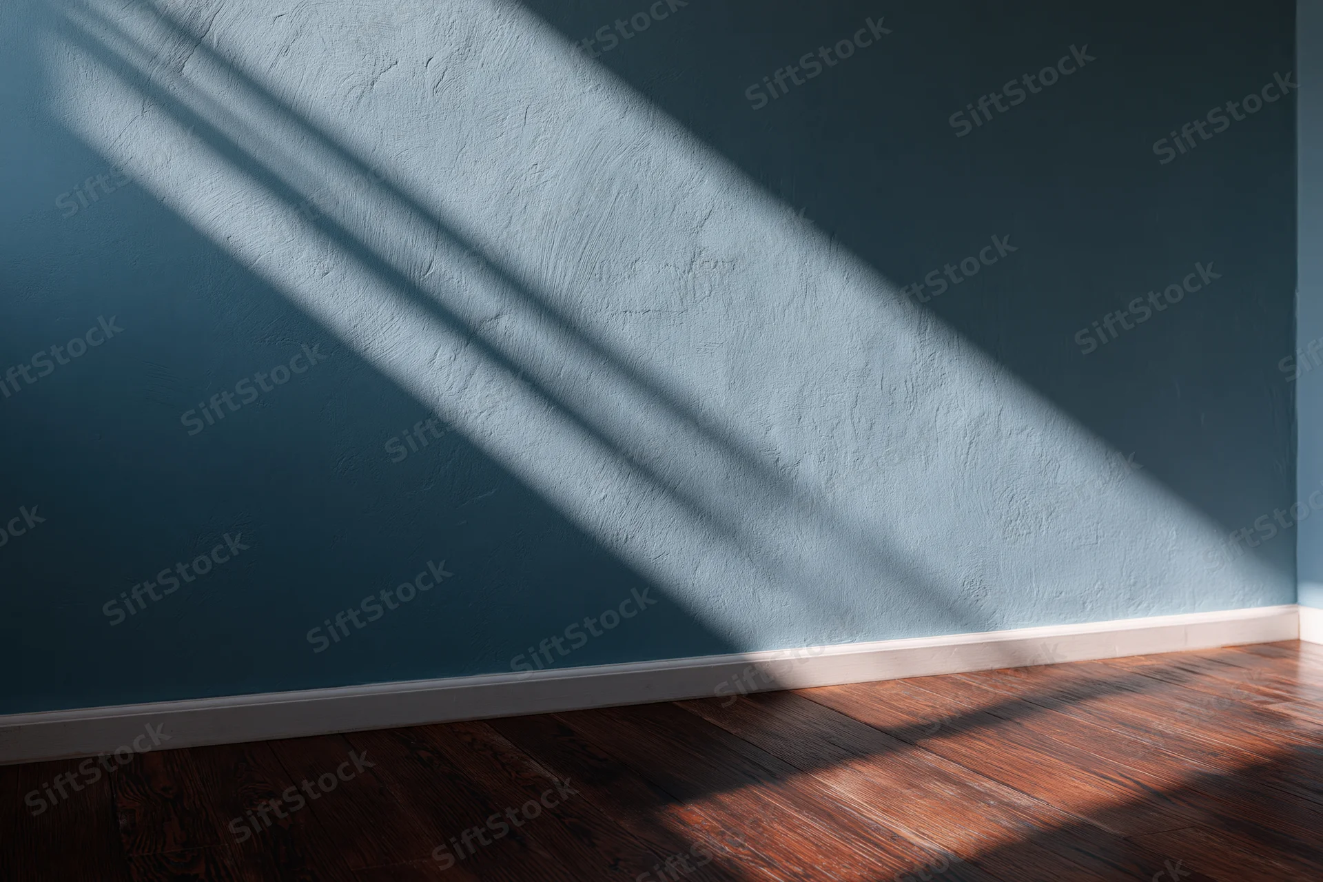Empty interior room with dark teal-grey painted wall and wooden floor showing sunlight and shadows in corner