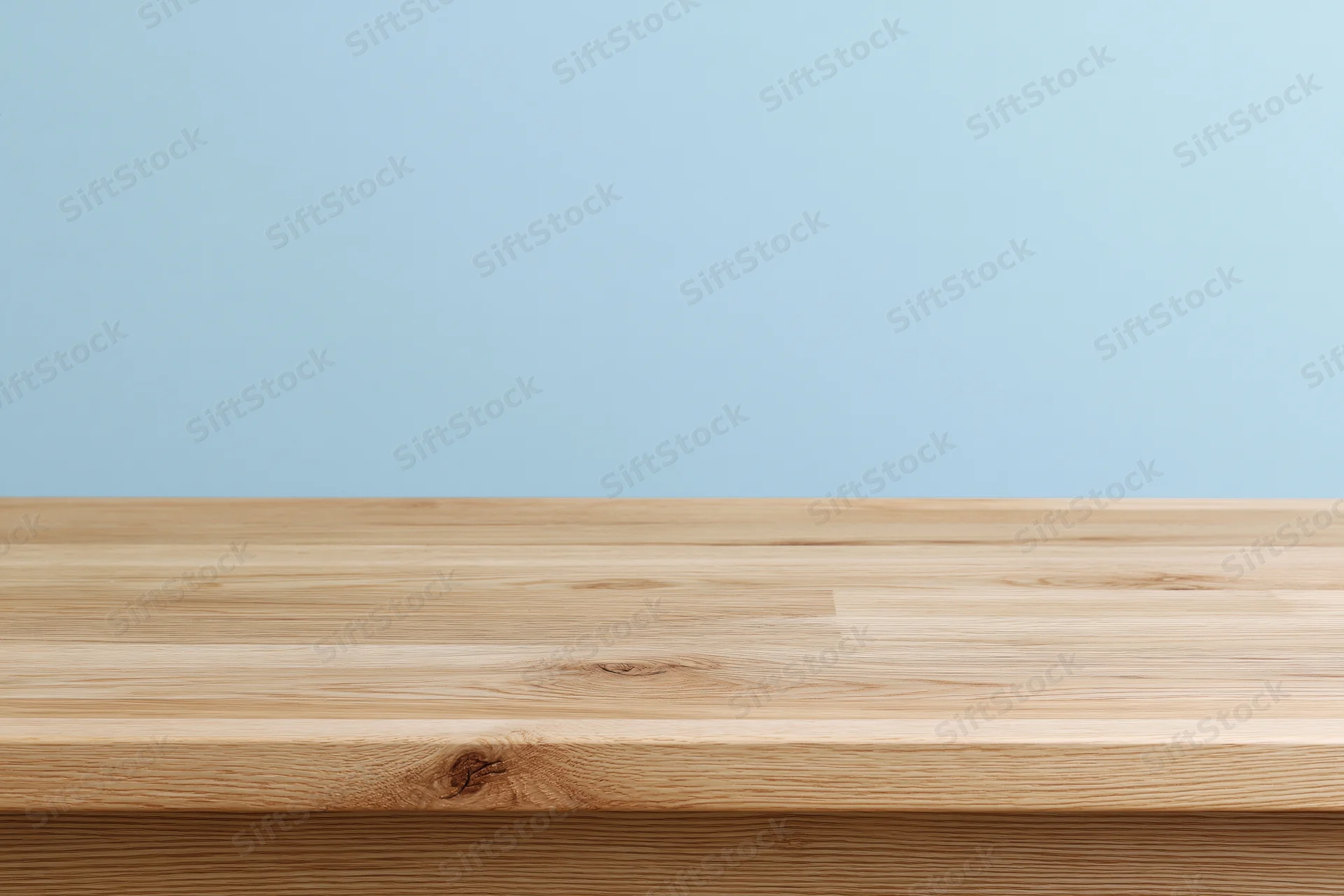 Empty light oak wooden tabletop surface against a plain blue background with copyspace for product display