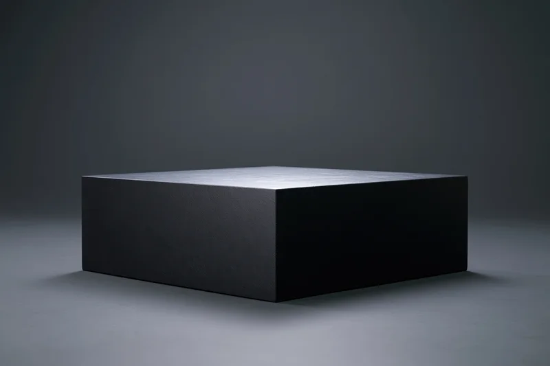 Matte black rectangular display pedestal centered on a gray studio floor