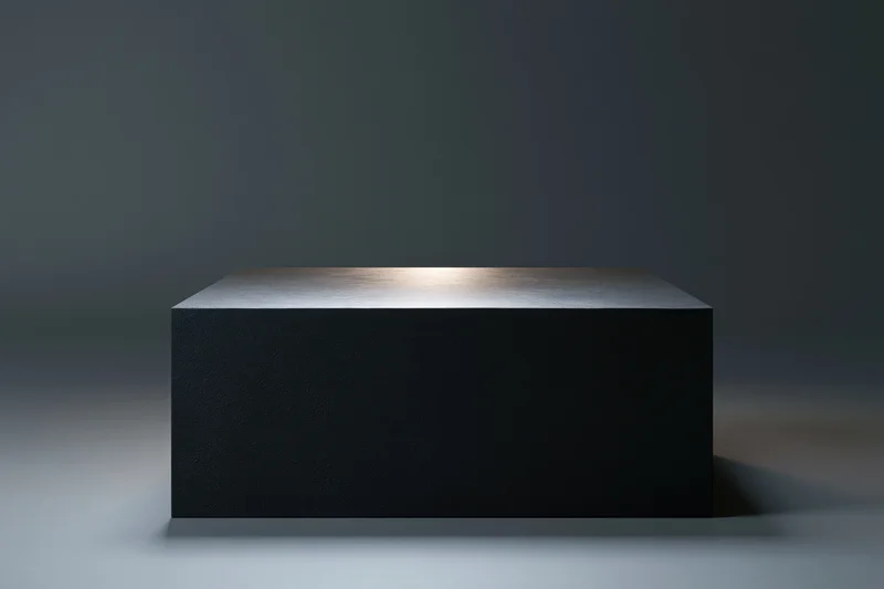 Matte black rectangular pedestal centered in a studio space with spotlight and gradient background