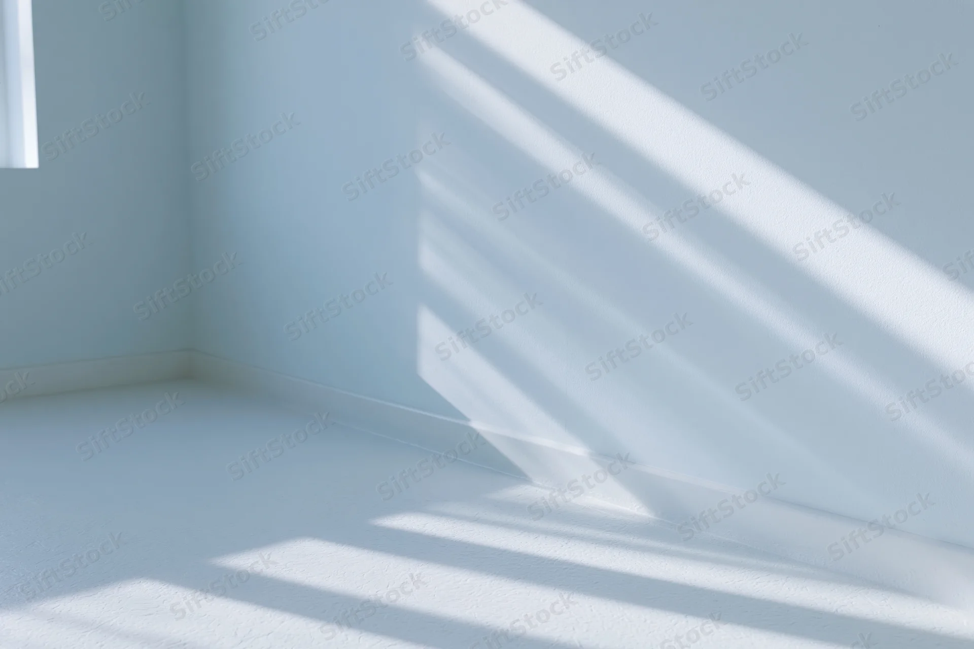 Empty minimalist room with pale blue-white walls and sunlight casting diagonal shadows across floor and wall corner