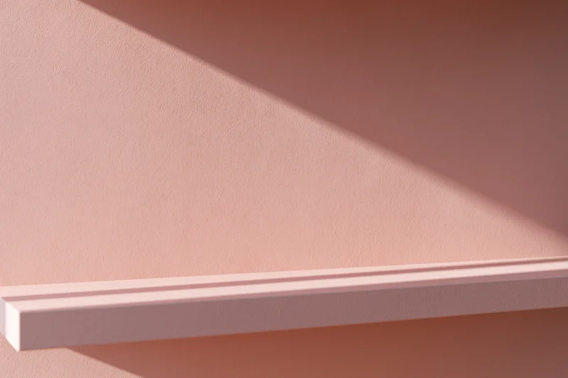 Empty pale pink shelf mounted on a matching matte pink wall in a minimalist interior
