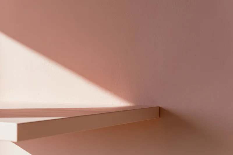 Empty blush-pink shelf mounted on a matching matte pink wall in a minimalist interior