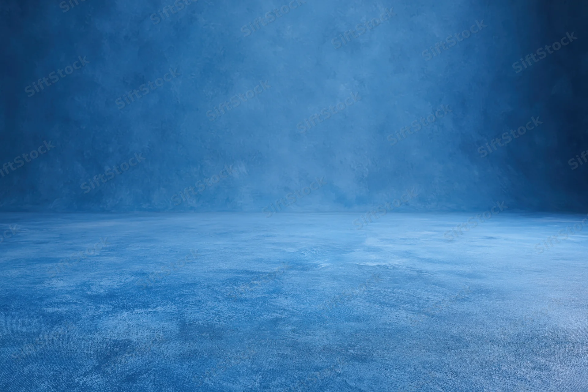 Seamless blue painted canvas backdrop for studio photography with empty floor and wall space