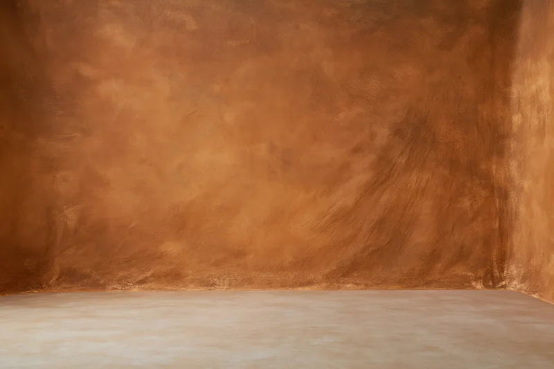 Warm hand-painted muslin backdrop in a studio corner with copyspace for photography