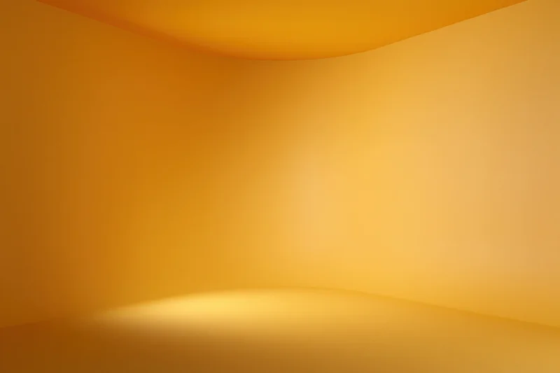 Empty curved studio corner with smooth orange-yellow gradient backdrop and floor