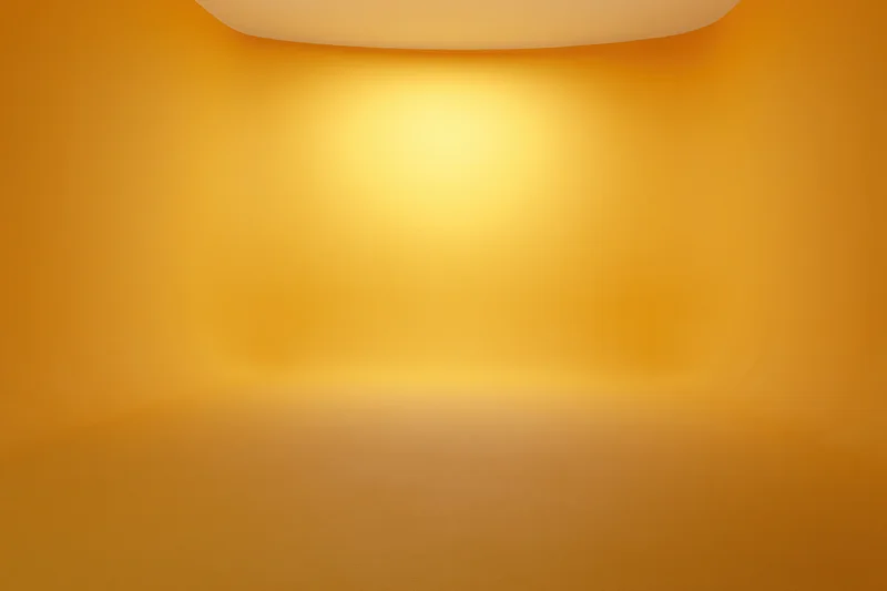 Seamless golden studio backdrop with curved wall-to-floor transition and soft ambient lighting