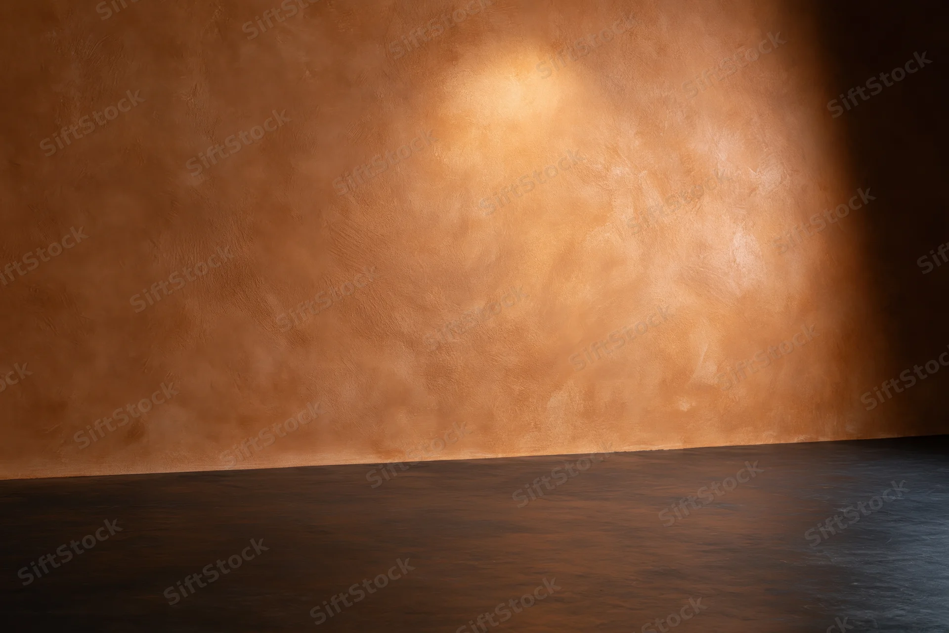 Textured painted canvas wall meeting dark floor in empty studio space under warm spotlight