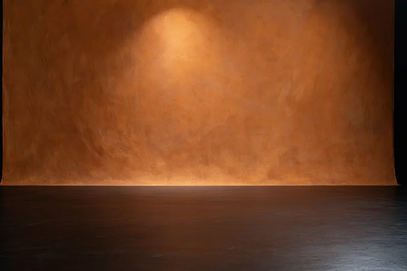 Textured painted canvas wall with warm spotlight and dark floor in empty studio backdrop