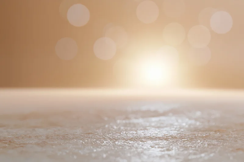 Soft golden bokeh light over smooth textured surface in studio backdrop