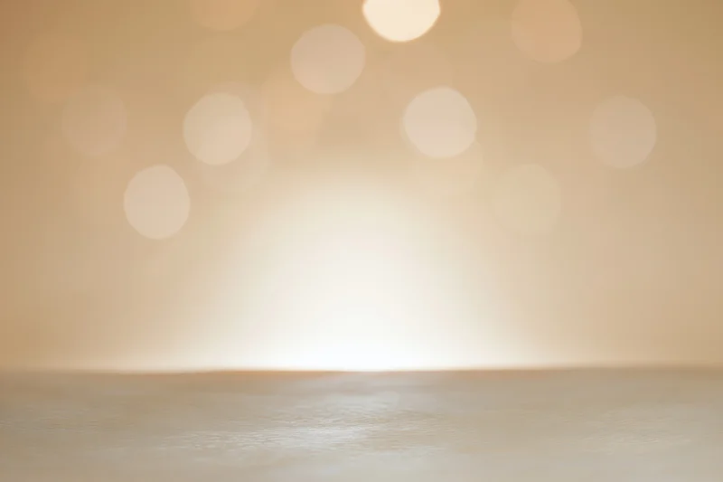 Empty studio backdrop with soft golden bokeh lights and wooden floor surface
