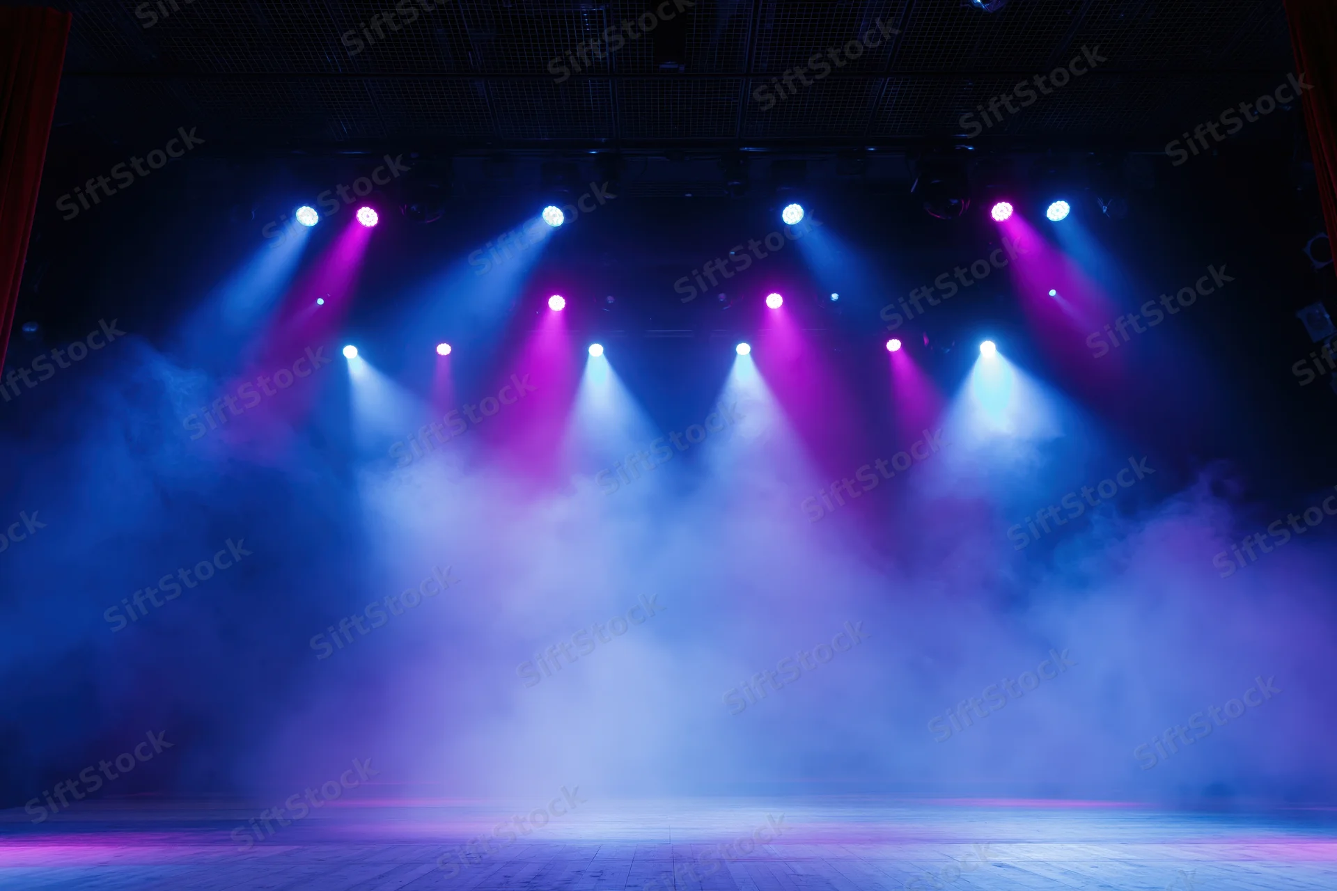 Empty theater stage illuminated by blue and purple spotlights with fog, viewed from front of house