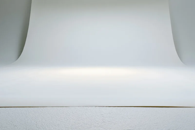 Seamless white paper backdrop curved over a textured surface in a photography studio