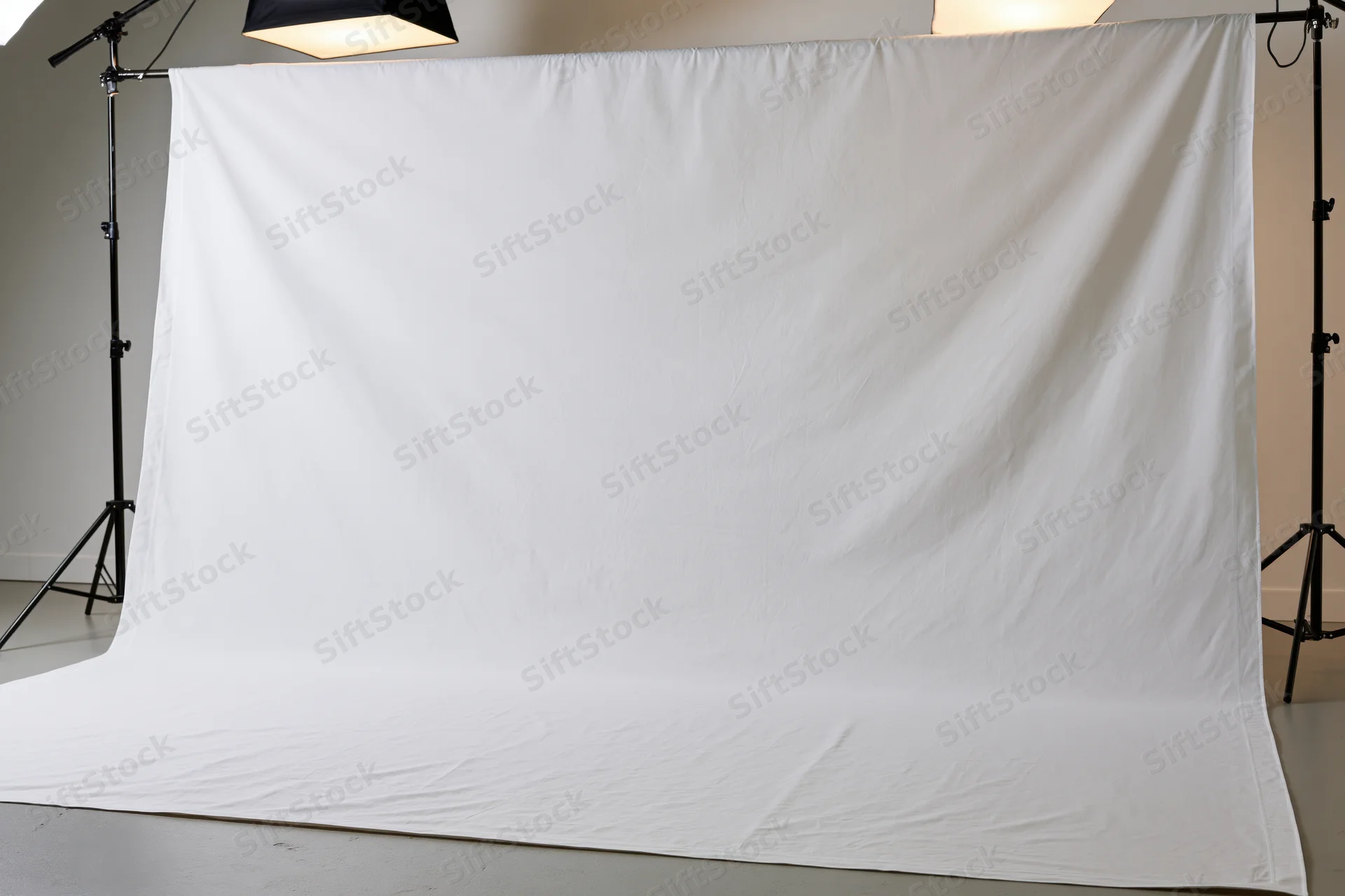 Seamless white fabric backdrop stretched across studio floor and wall with lighting stands and softboxes above