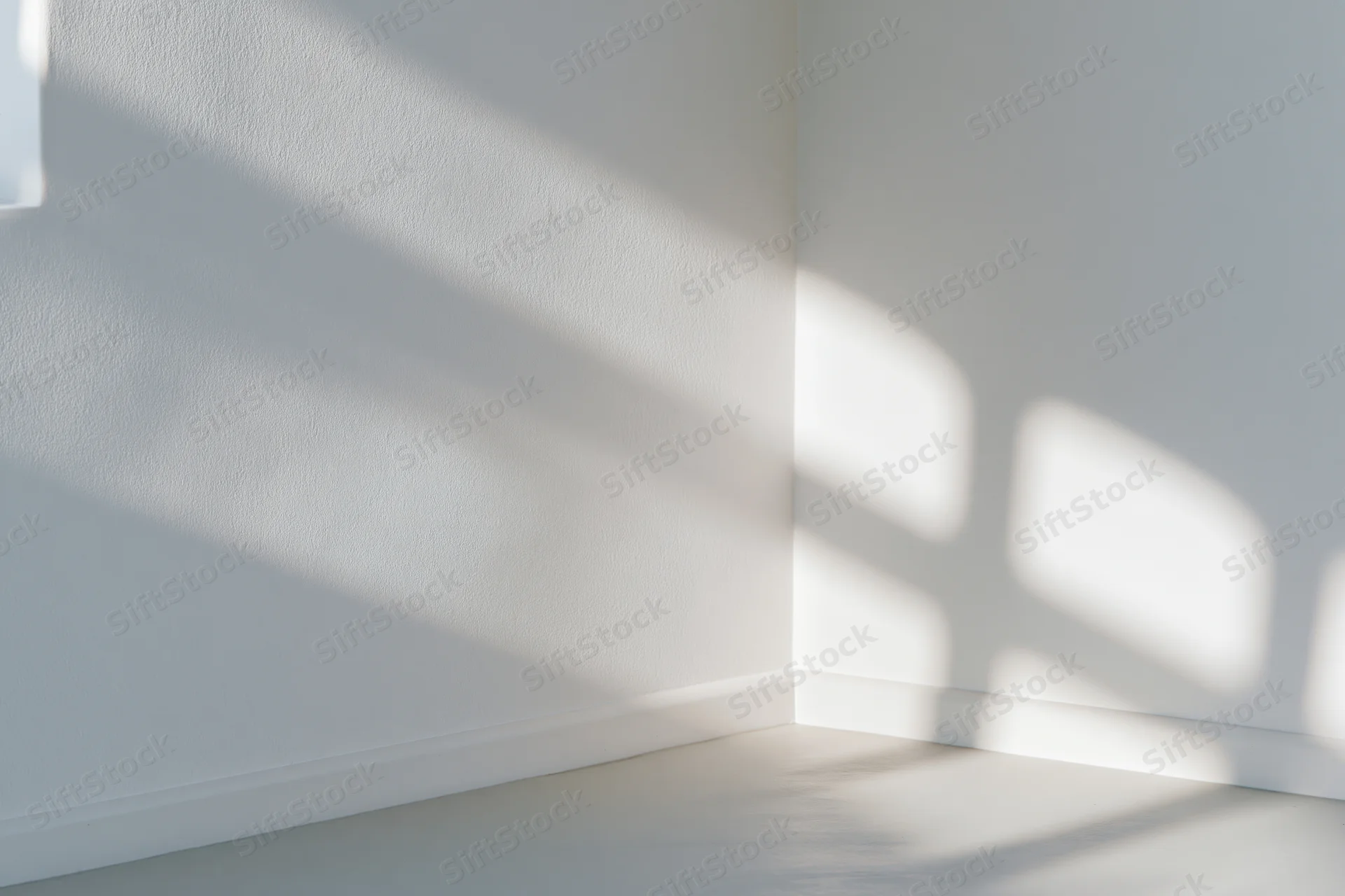 White room corner with sunlight casting shadows on wall and floor