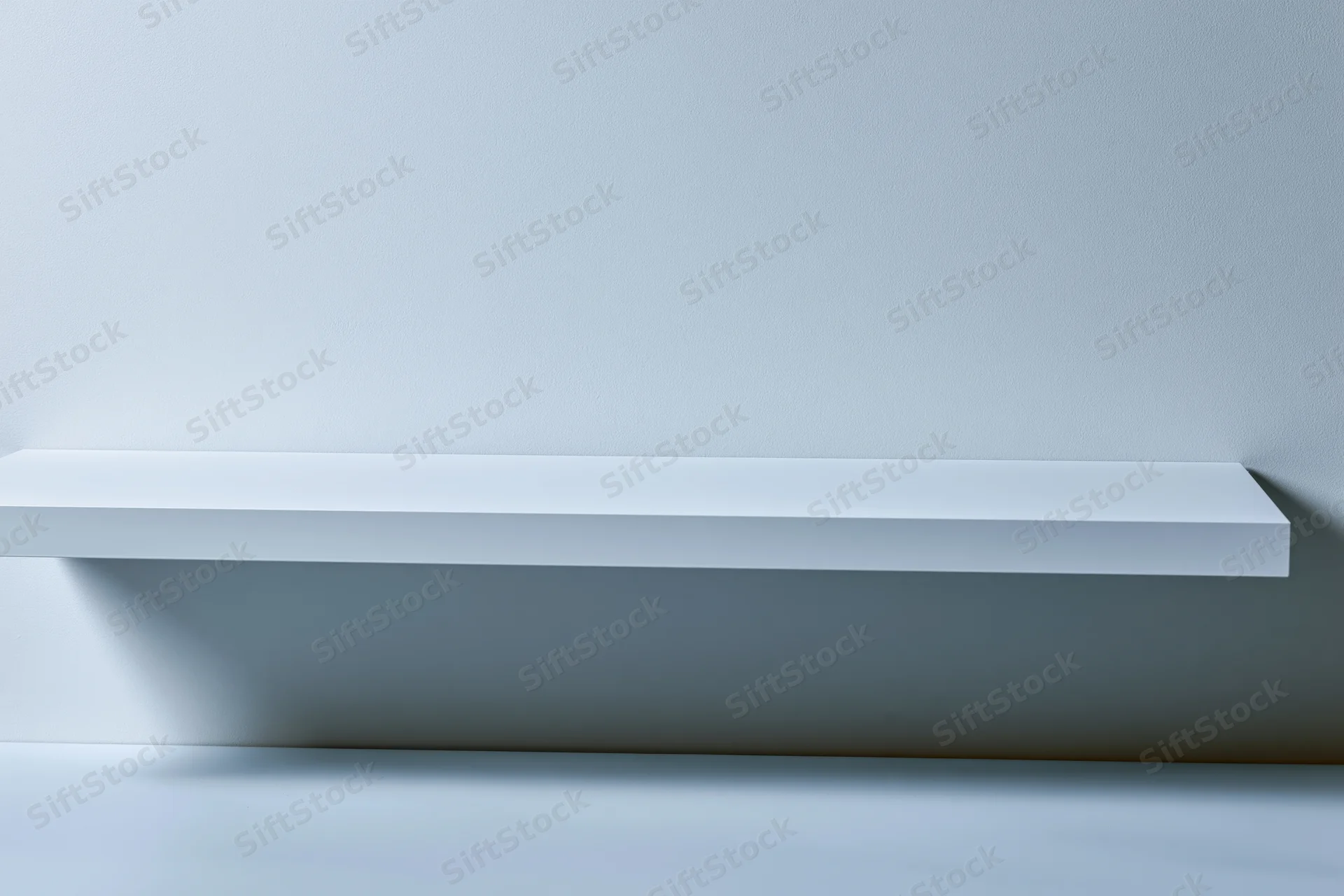 Empty white shelf mounted on a plain light gray wall in a studio setting