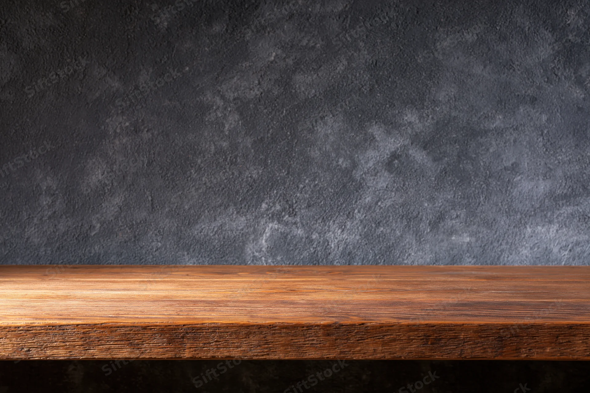 Empty wooden shelf against dark textured wall with copyspace for display