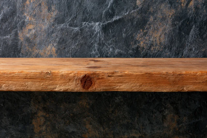 Empty worn wooden shelf surface against dark stone wall