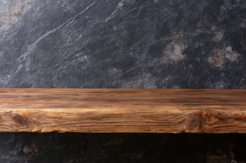 Empty rustic wooden shelf mounted on dark stone wall with copyspace for display