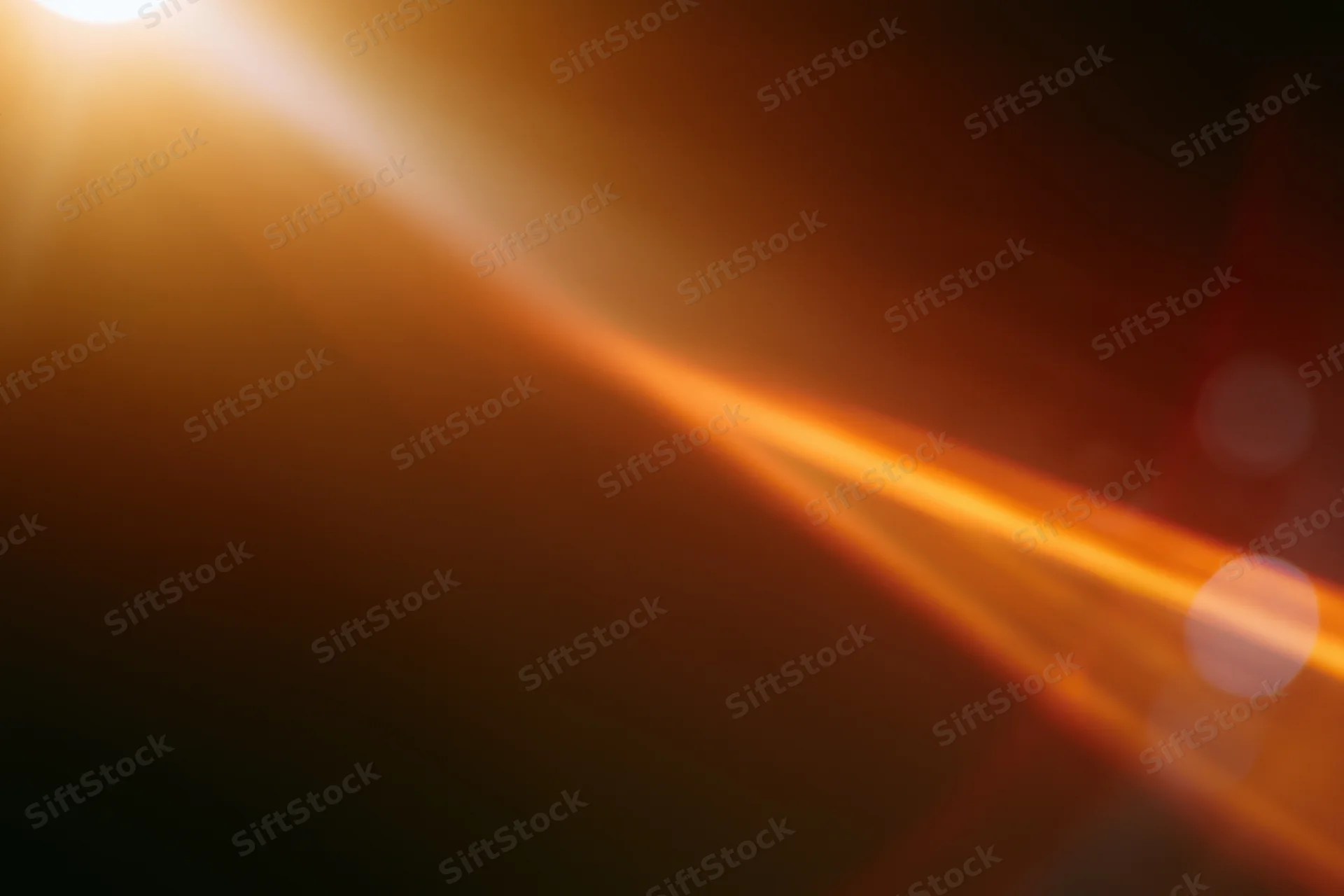 Warm light source creating lens flare and bokeh in abstract closeup