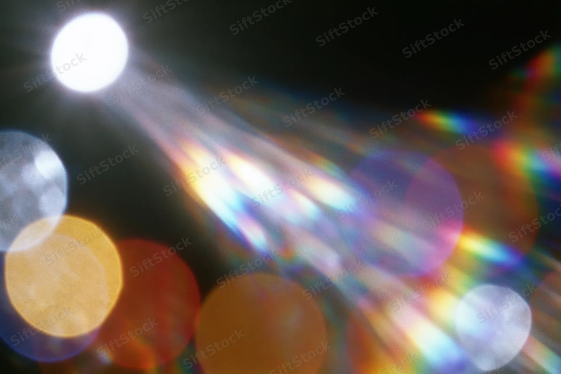 Abstract lens flare and bokeh light scatter with rainbow spectrum against dark background