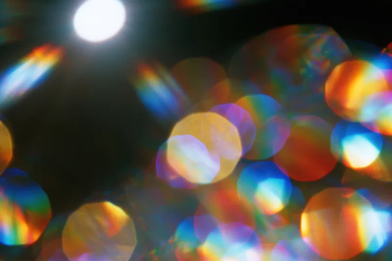 Abstract lens flare and bokeh light scatter with rainbow refraction patterns in soft focus