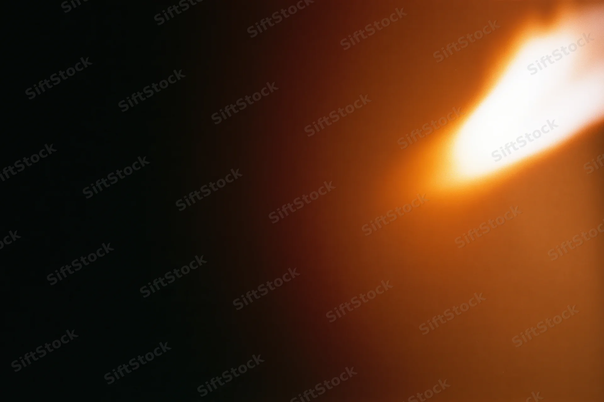 Close-up of a flickering candle flame glowing warmly against a dark background