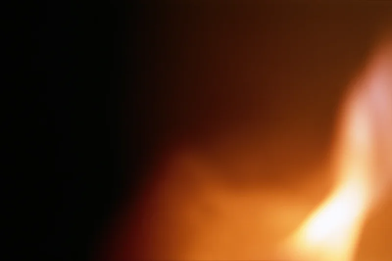 Extreme close-up of a flickering candle flame glowing warmly in dim light