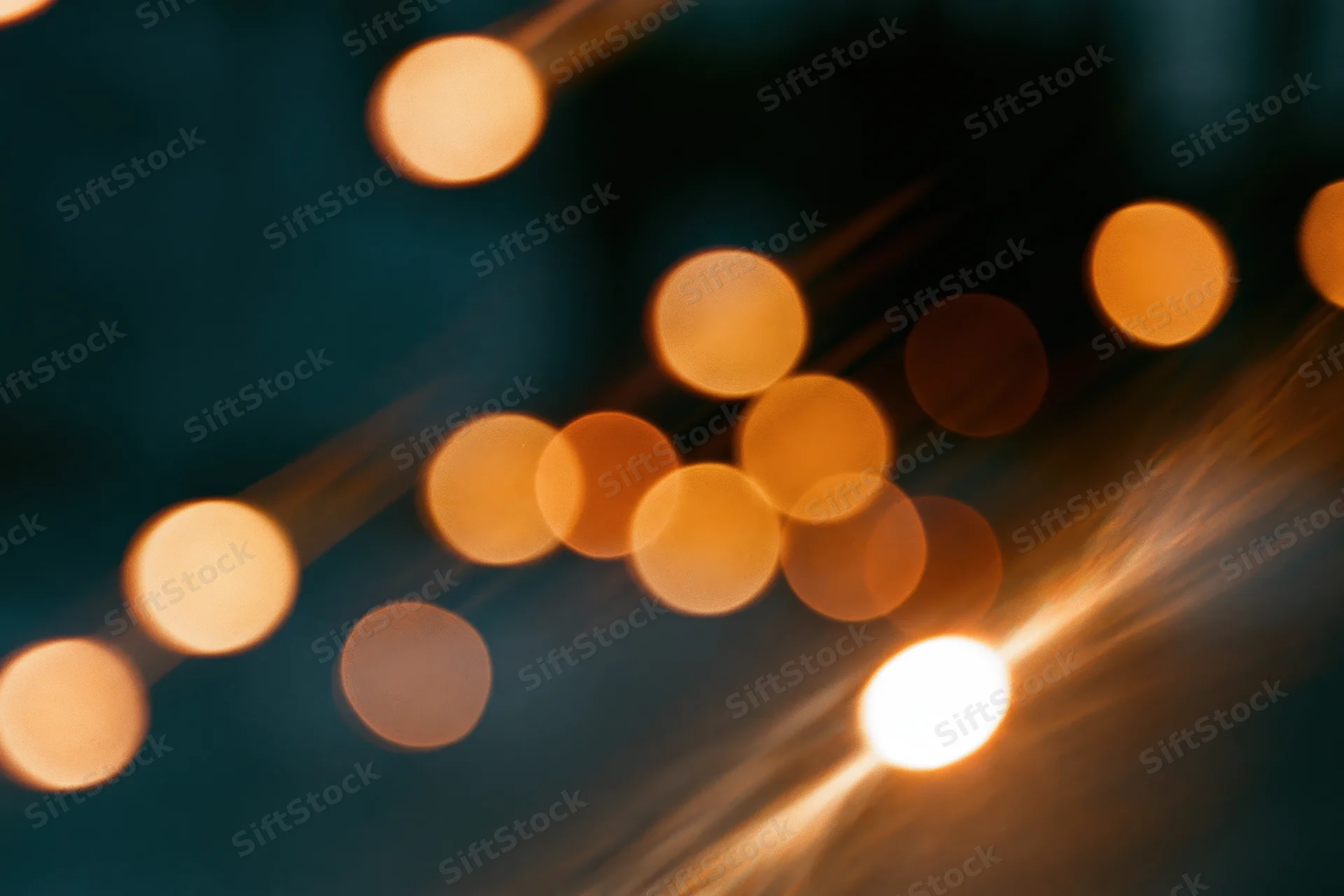Warm out-of-focus lights arranged in a diagonal pattern against a dark background with soft glow and lens flare