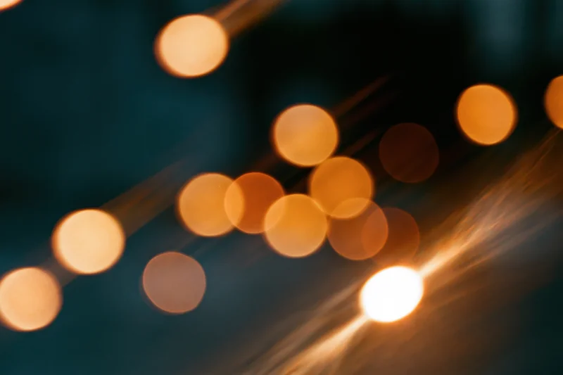 Warm out-of-focus lights arranged in a diagonal pattern against a dark background with soft glow and lens flare
