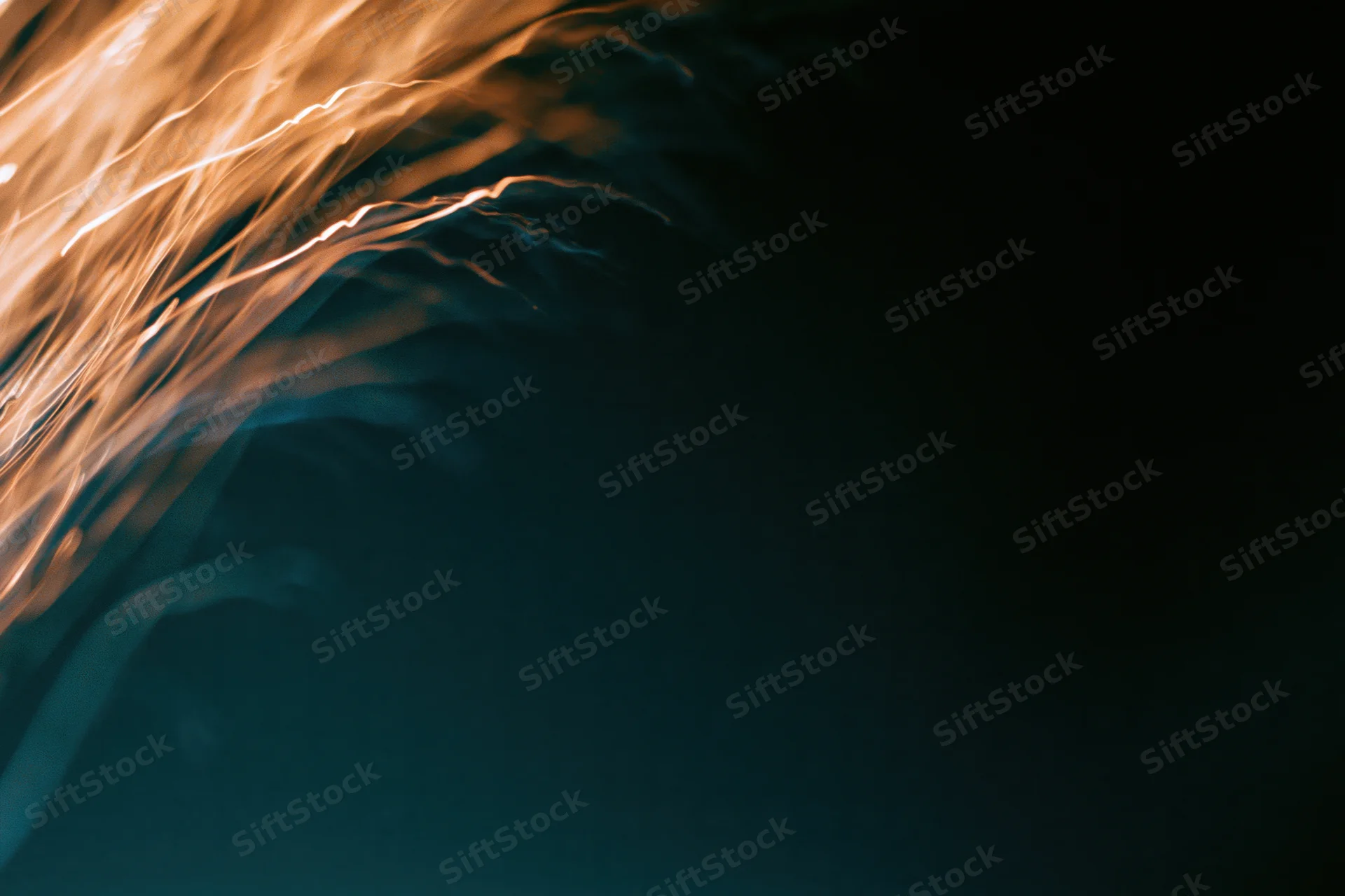 Warm amber light streaks flowing in abstract motion against dark background