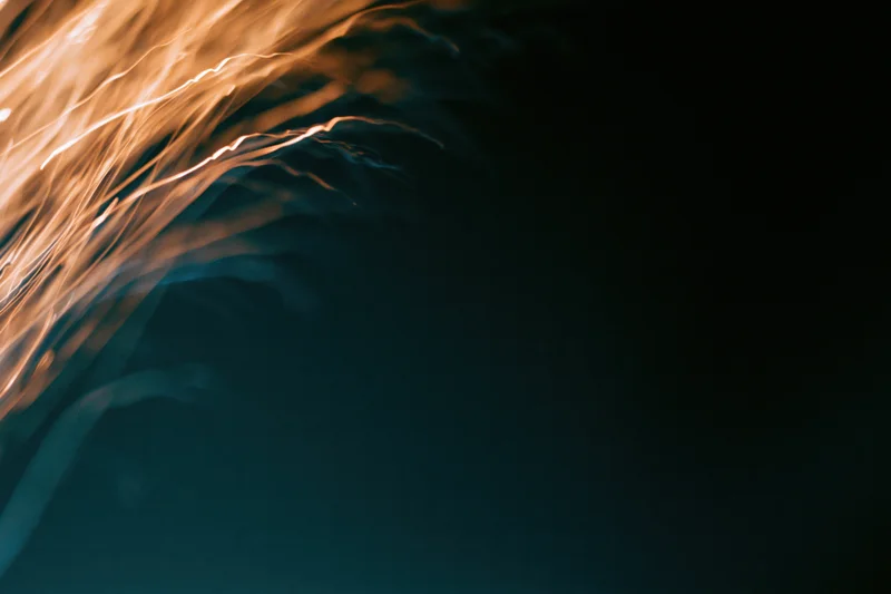 Warm amber light streaks flowing in abstract motion against dark background